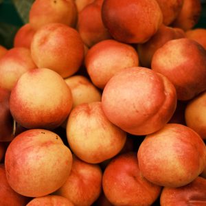 A vibrant pile of ripe peaches displayed at an outdoor market stand.