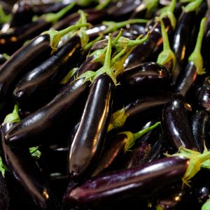 Close-up of fresh organic eggplants piled at a market display.